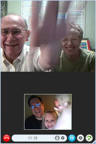 A video call where a grandaughter is holding a doll near the camera and, in the other screen, the grandfather is pretending to reach for it