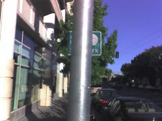 A street sign almost totally blocked by a pole closely in front of it
