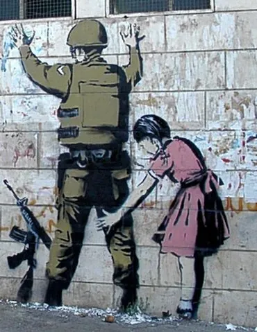 A Banksy stencil on Israel’s West Bank barrier. It has a soldier against the wall, being patted-down for weapons by a little girl.
