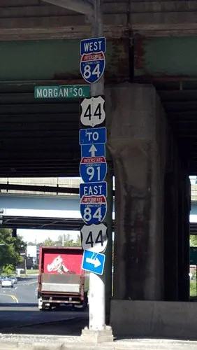 A single pole has the following road signs on it, top to bottom: West Interstate 84, State 44, Interstate 91, East Interstate 84, State 44 (again)