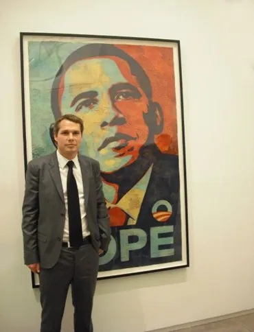 Shepard Fairey posing in front of his “Hope” portrait of President Obama