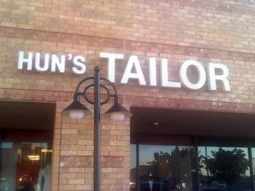 A storefront with the sign “Hun’s Tailor” above