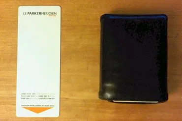 A Le Parker Méridien room-key card next to a wallet. The card is narrower and taller than the wallet.