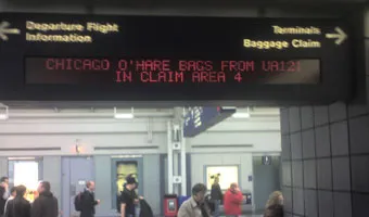 An electronic sign saying “CHICAGO O'HARE BAGS FROM UA121 IN CLAIM AREA 4”