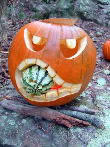An pumpkin carved so it’s angrily eating a squash